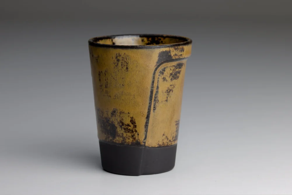 Geel-bruine keramische beker met zwarte basis