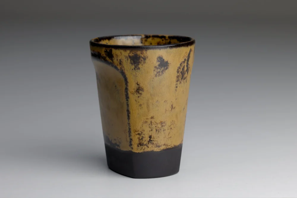 Geelbruine keramische beker met zwarte accenten