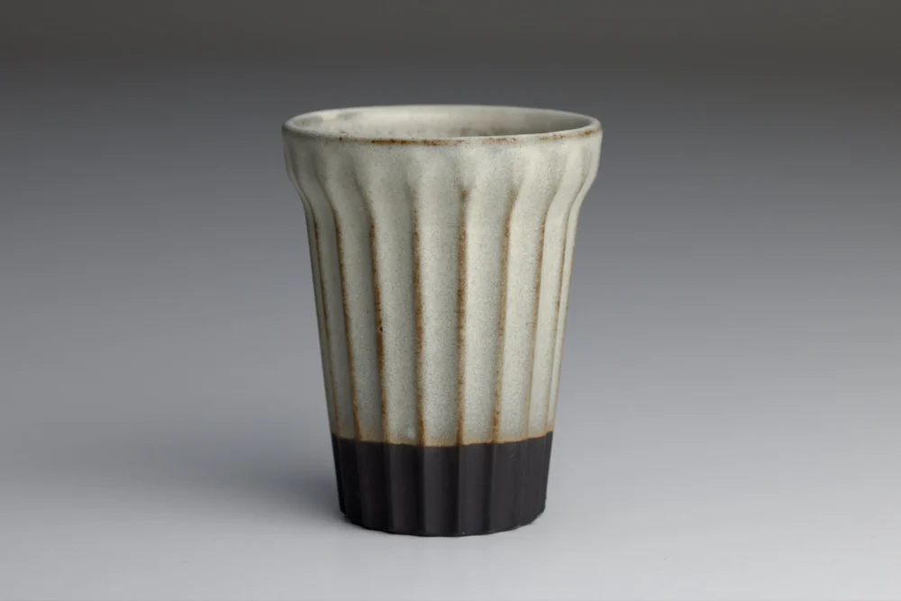 Geribbelde keramische beker op grijze achtergrond